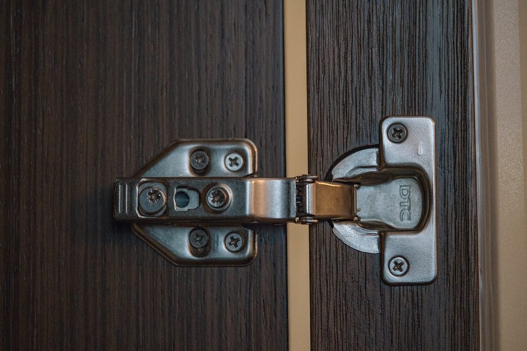 Metal hinge and screws on a wooden frame